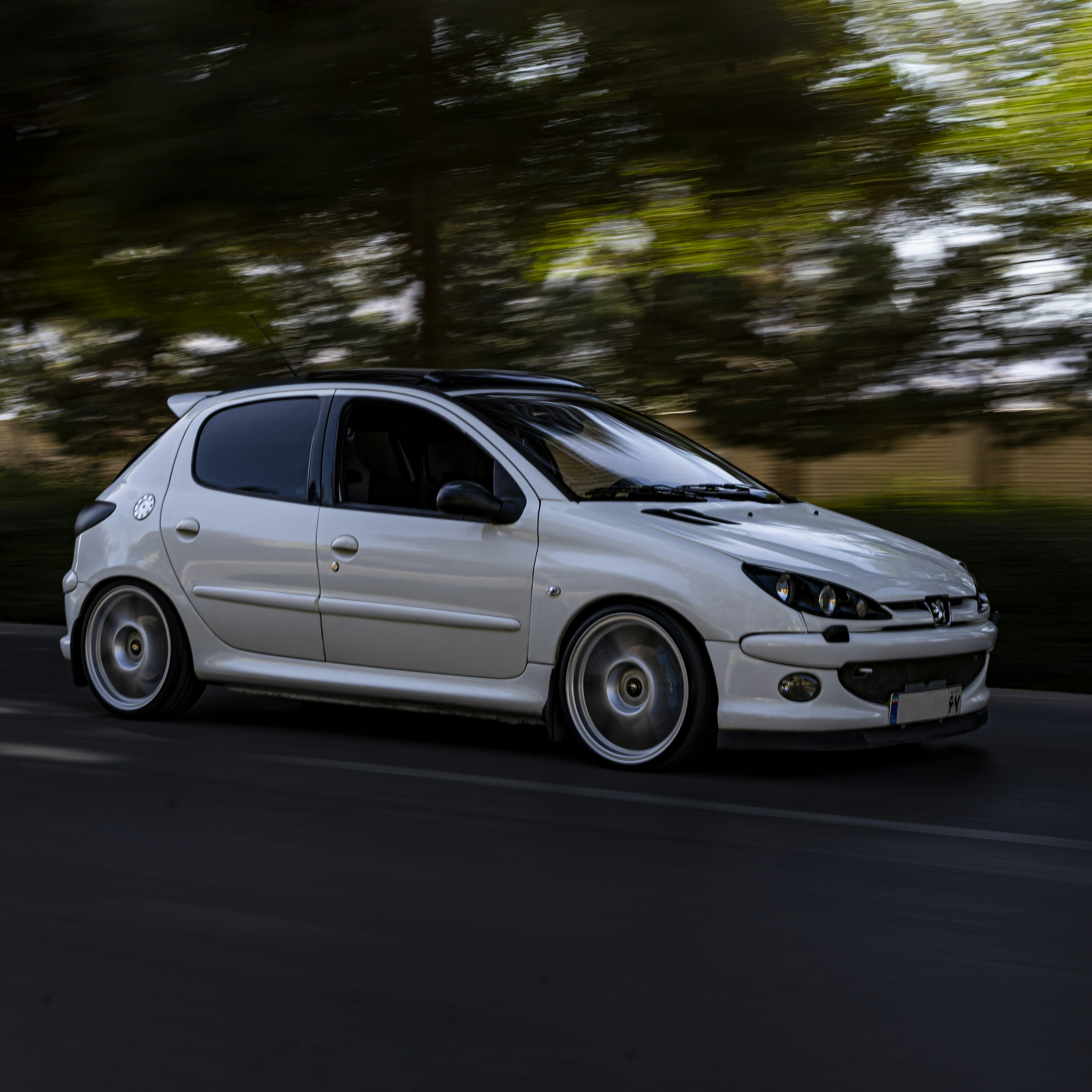 A small white car driving down a street