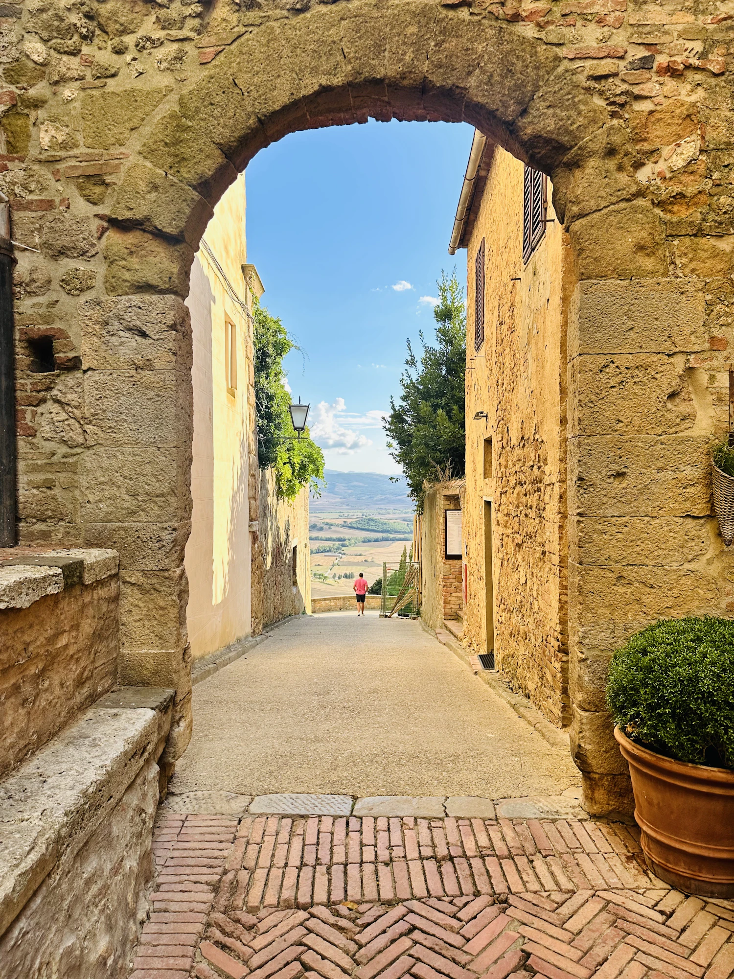 A narrow cobbled street running under a stone arch in an old Italian hill town