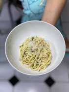 A person holding a bowl of spaghetti in their hand
