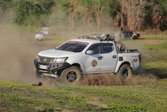 A white pick up truck driving down a dirt road
