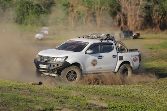 A white pick up truck driving down a dirt road