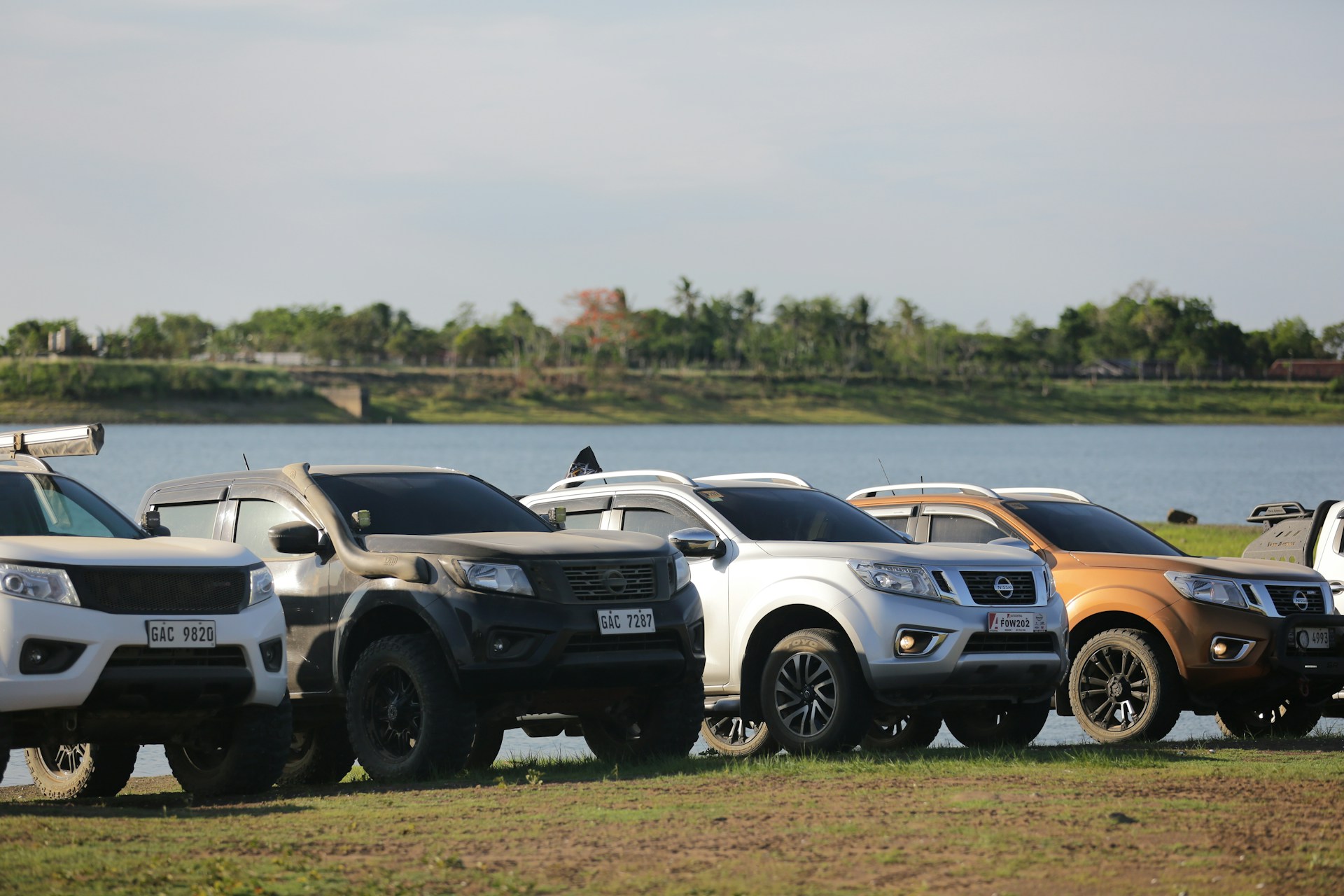 A row of trucks parked next to a lake