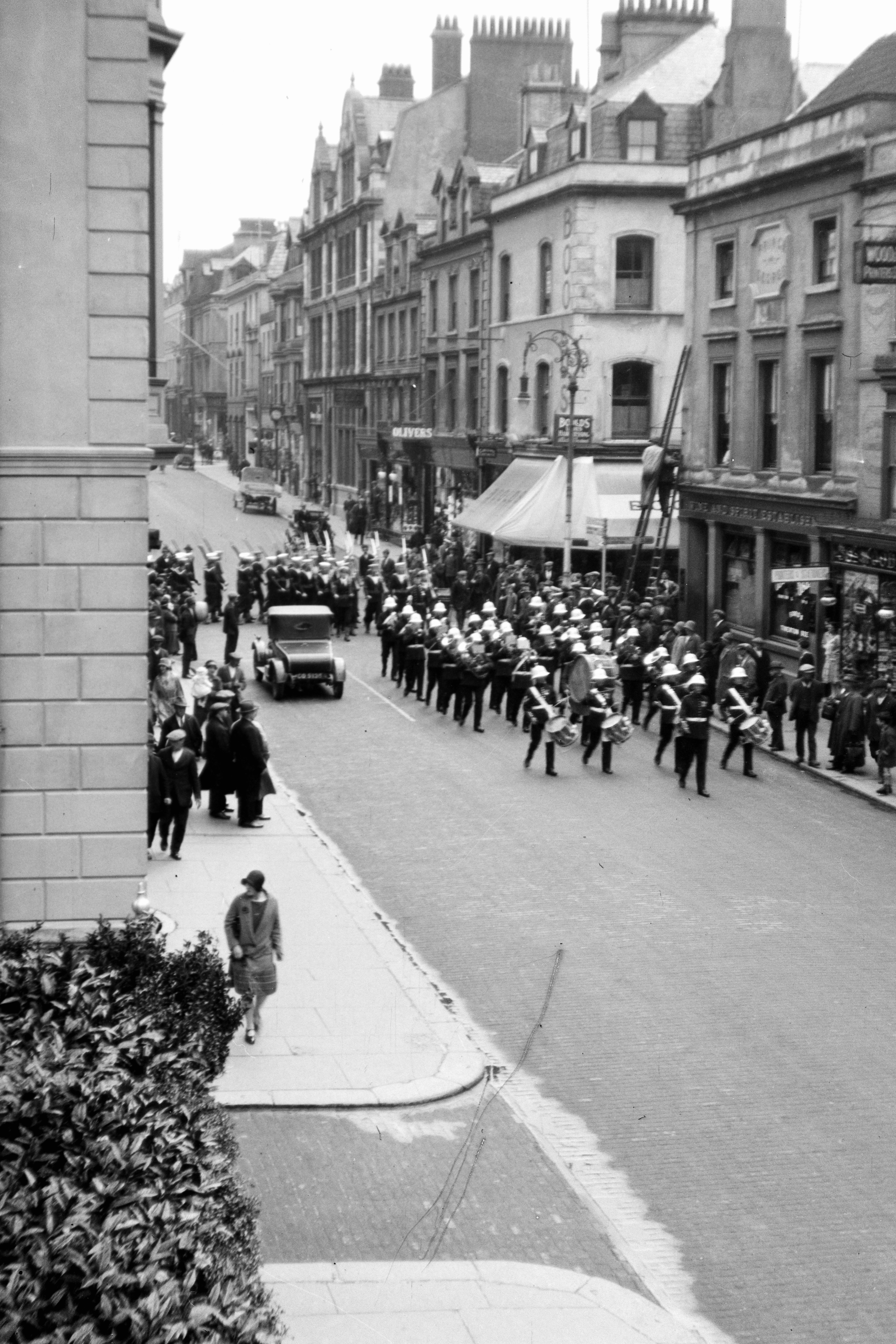 A group of people walking down a street next to tall buildings