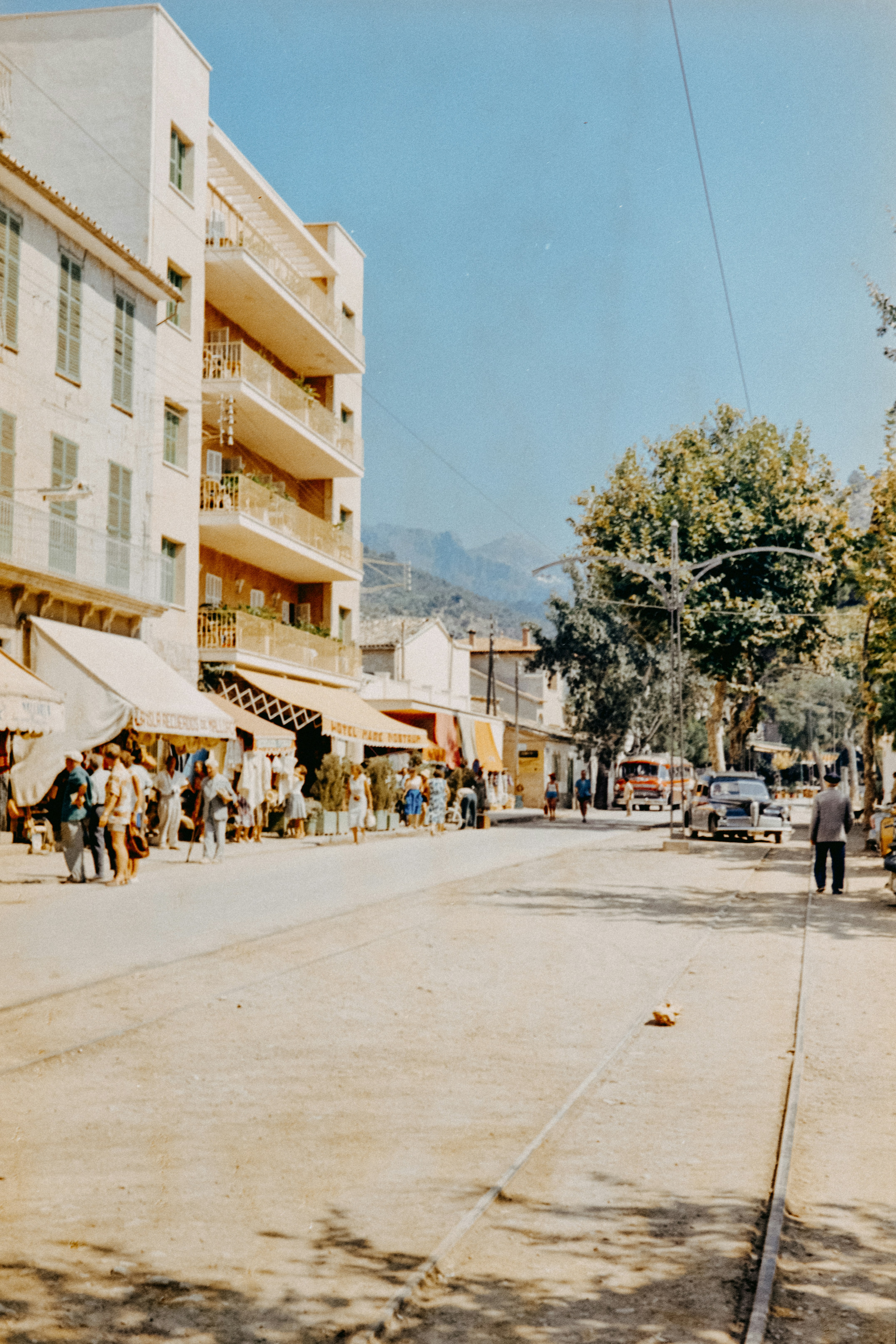 A group of people walking down a street next to tall buildings