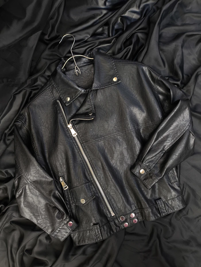 Black leather rider jacket laid on dark fabric