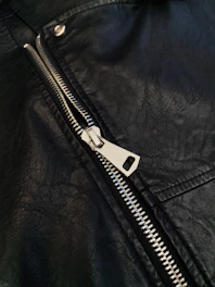 A close up of a black leather jacket with a zipper