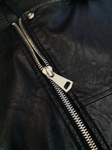 A close up of a black leather jacket with a zipper