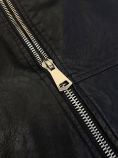 A close up of a zipper on a black leather jacket