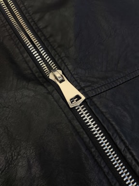 A close up of a zipper on a black leather jacket