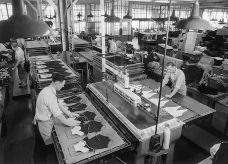 Workers operating machinery in a busy garment factory setting.