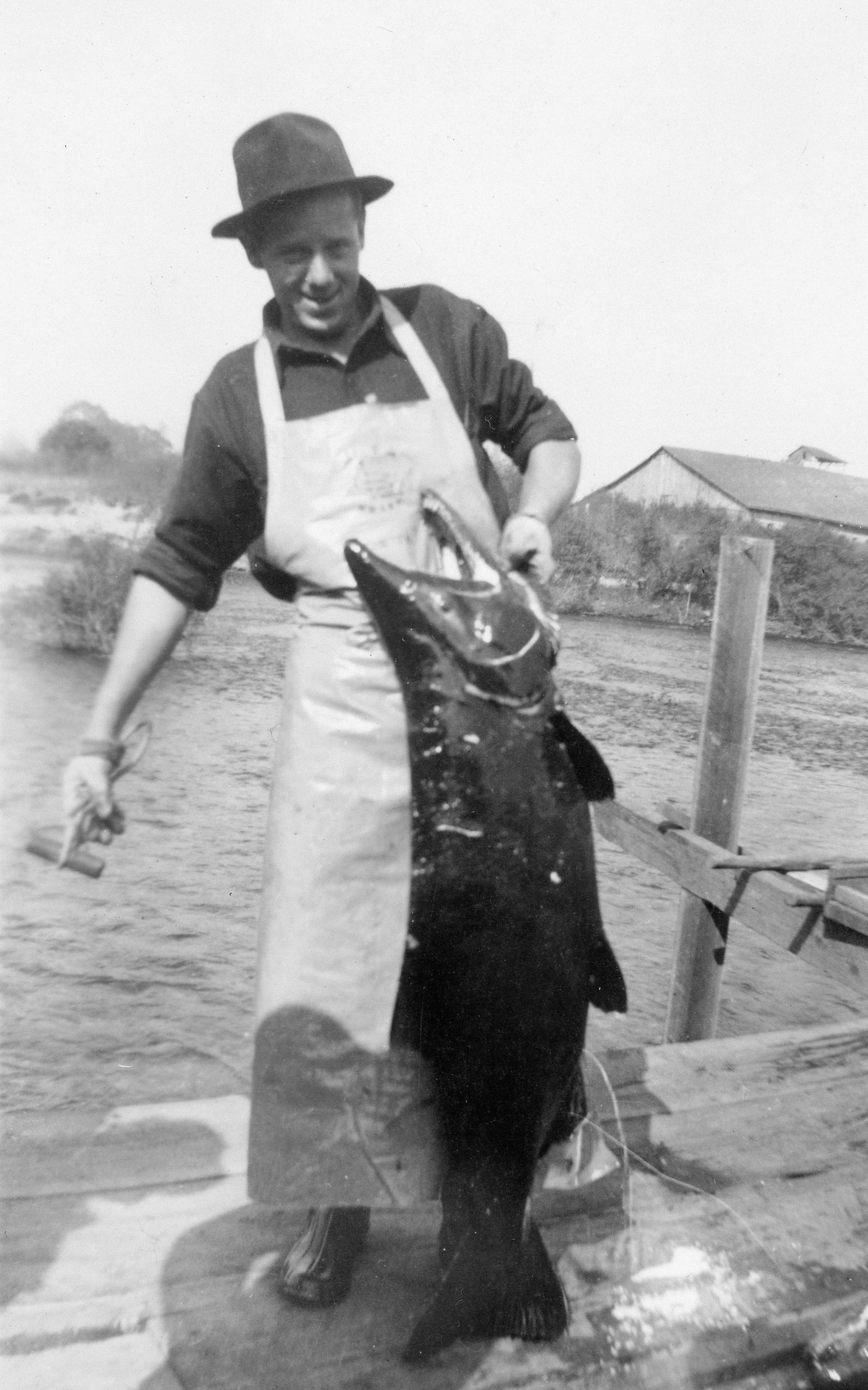 帽子とエプロンをかぶった男性が大きな魚を持った