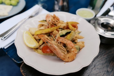 A white plate topped with shrimp and vegetables