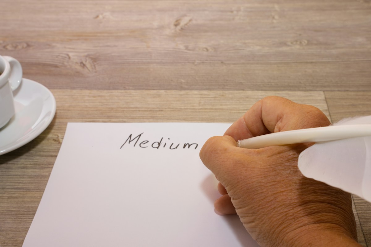Person writing on paper with a cup of coffee nearby, illustrating volunteer sign-up ideas for nonprofit recruitment.