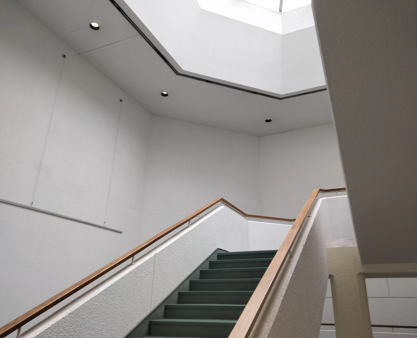 Pale stairwell with a skylight and a timber handrail
