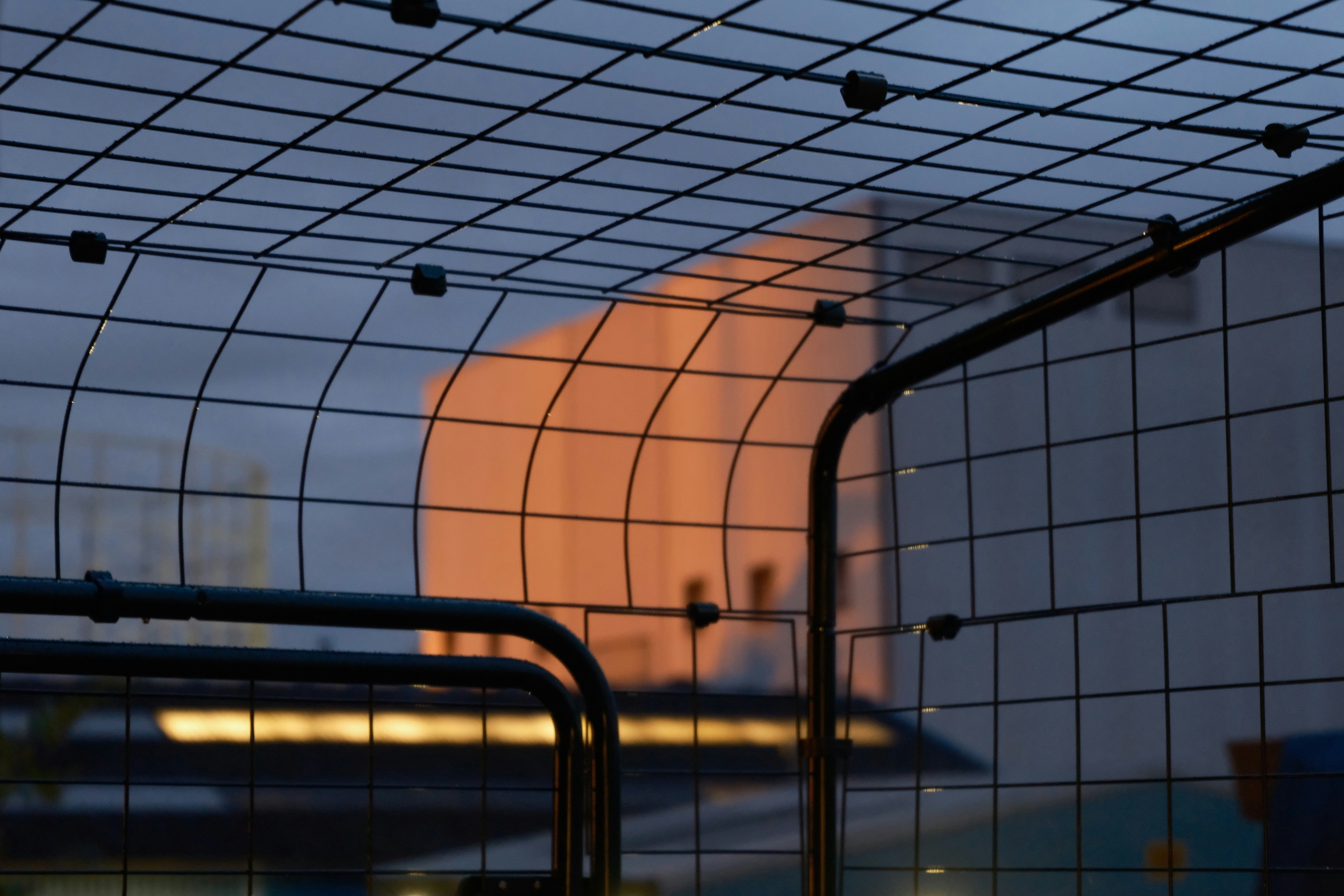 A close up of a fence with a building in the background