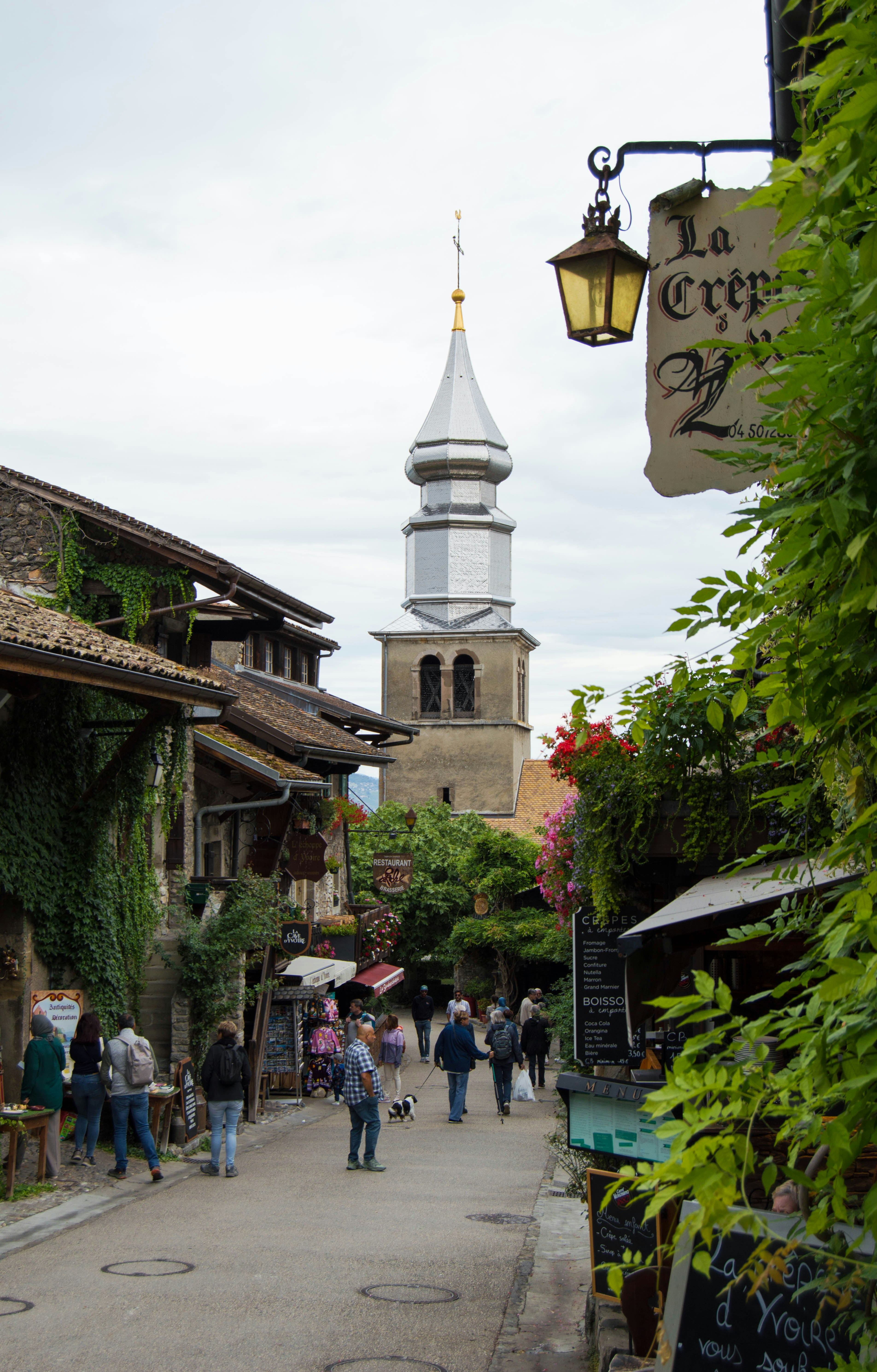 A street with people walking down it and a church in the background