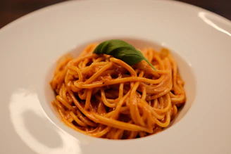 A white plate topped with pasta and sauce