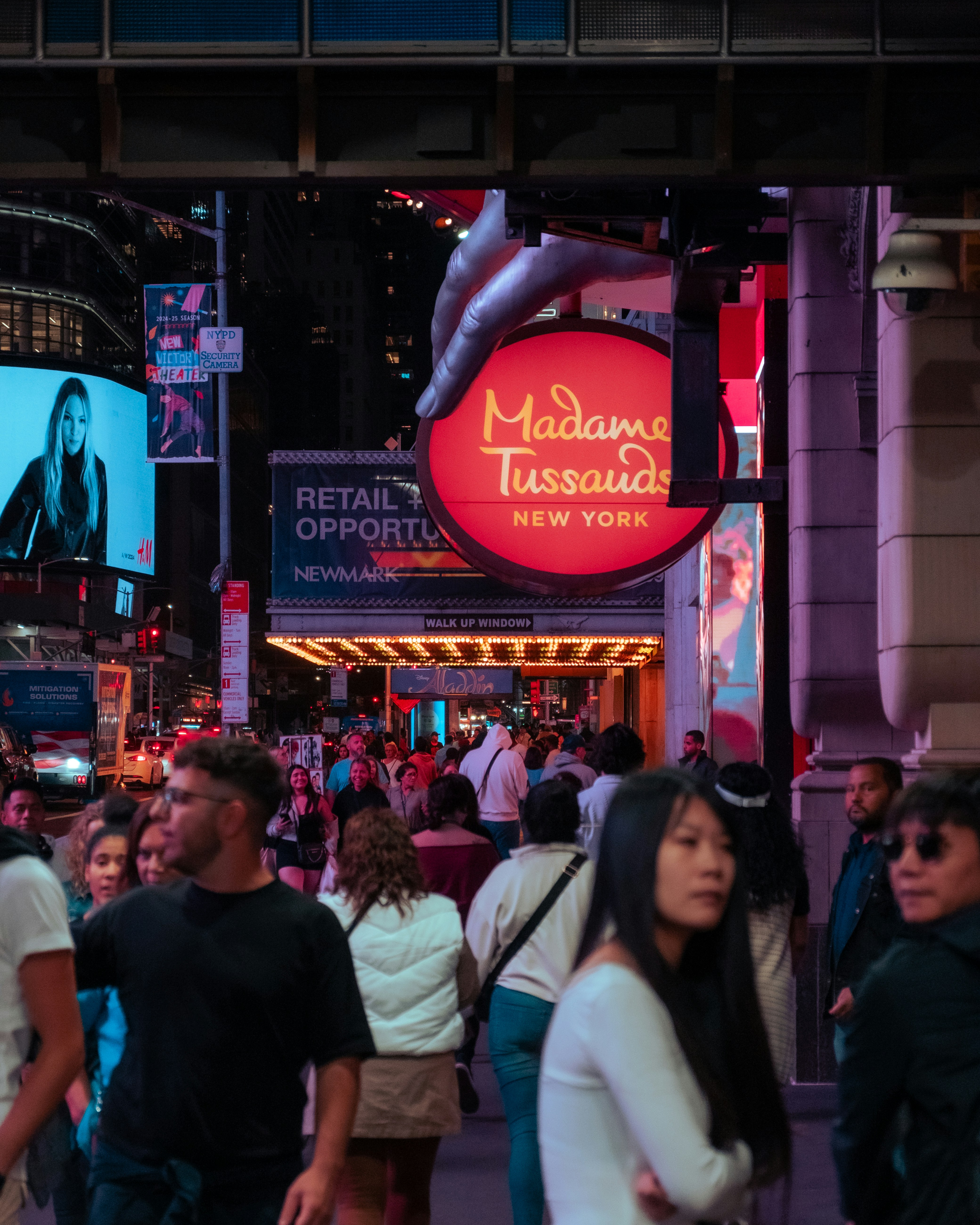 A crowd of people walking down a street next to tall buildings