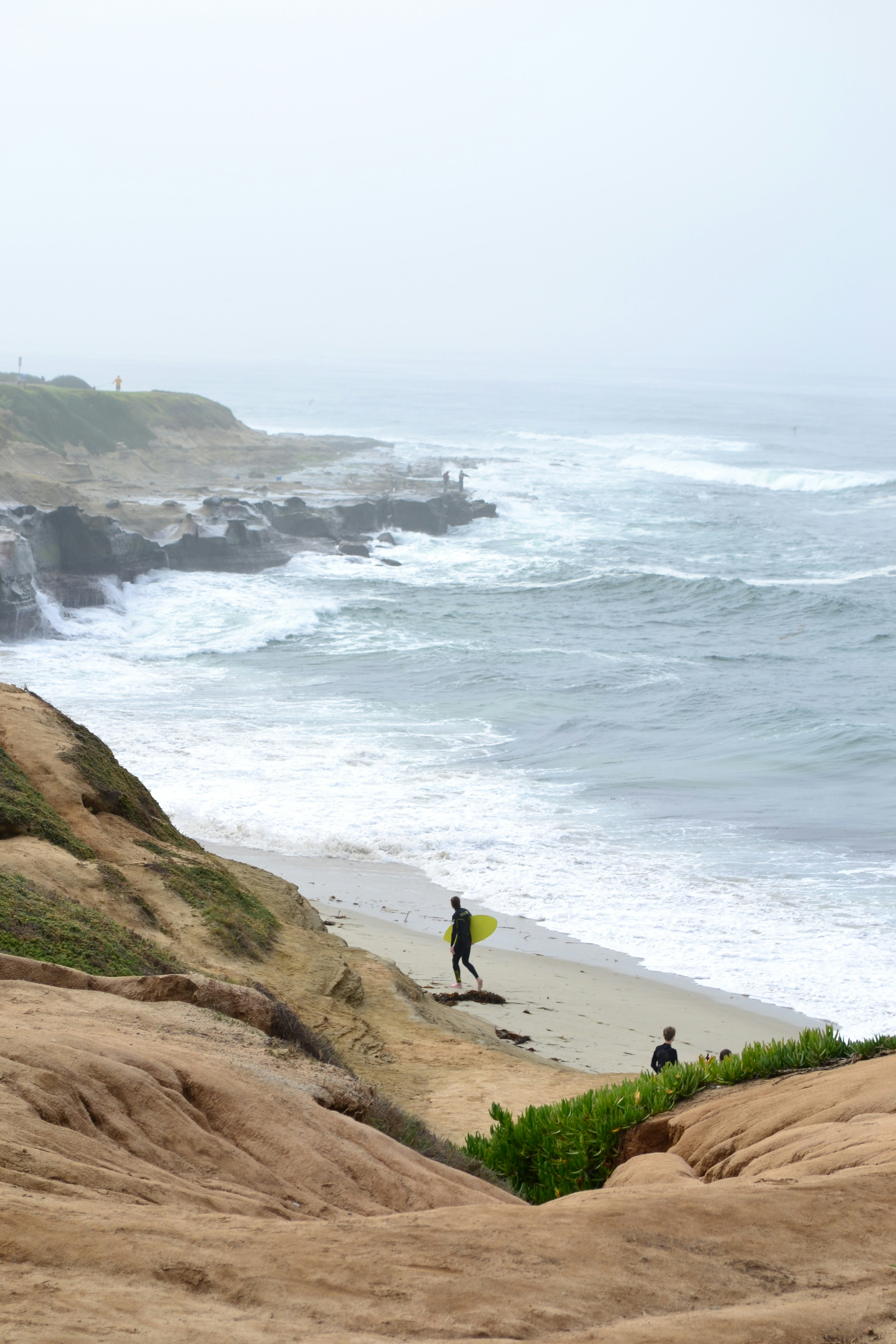 A person with a surfboard standing on a beach