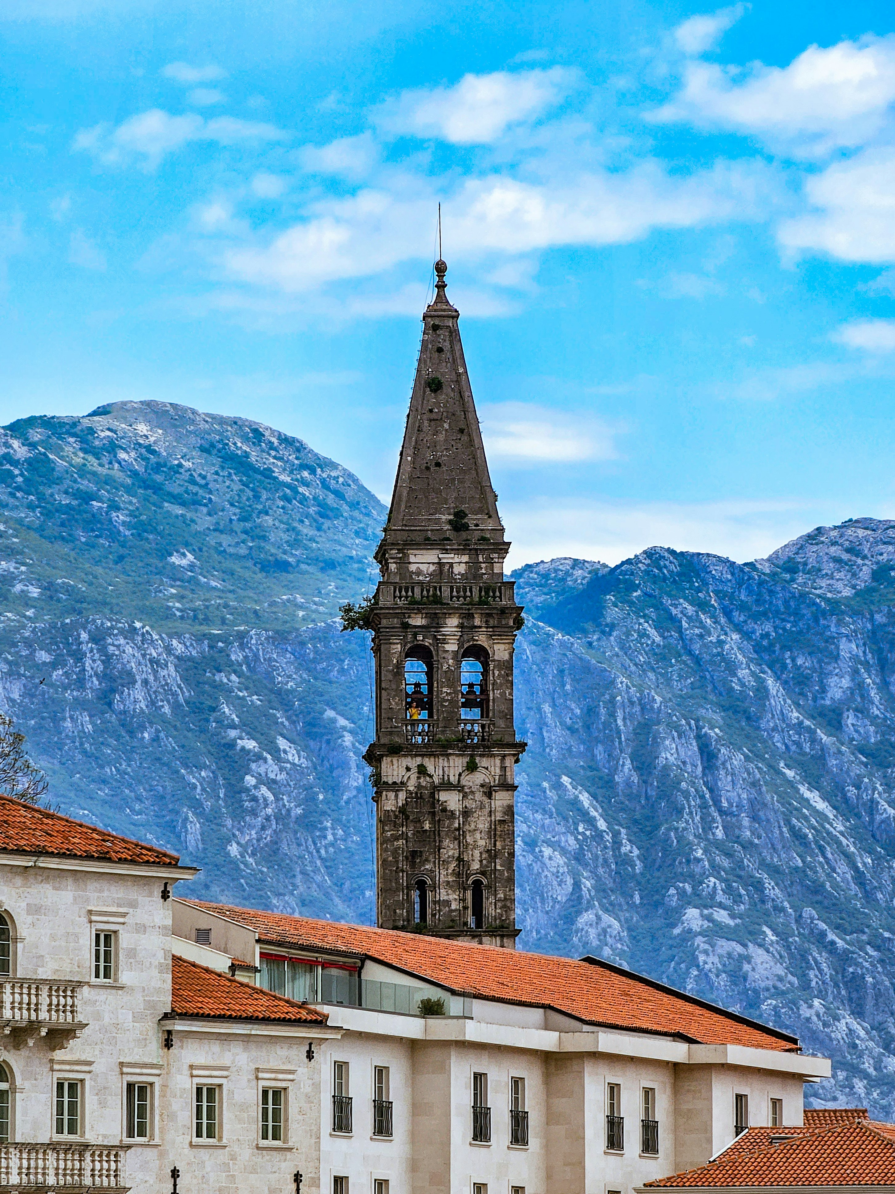 A clock tower towering over a city with mountains in the background