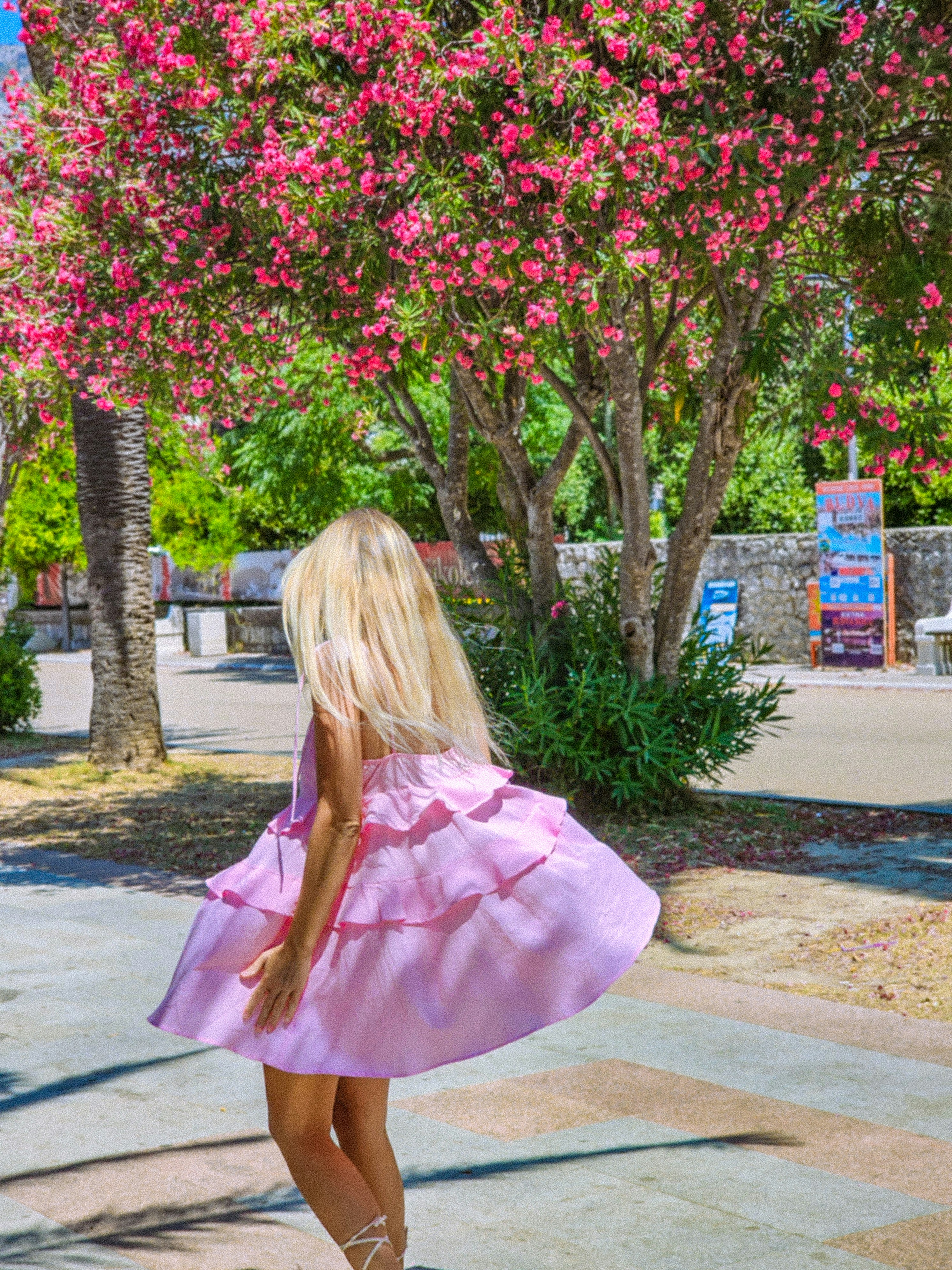 A woman in a pink dress walking down a sidewalk