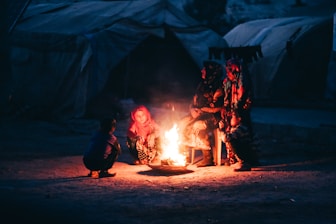 Two people sitting around a fire in a tent