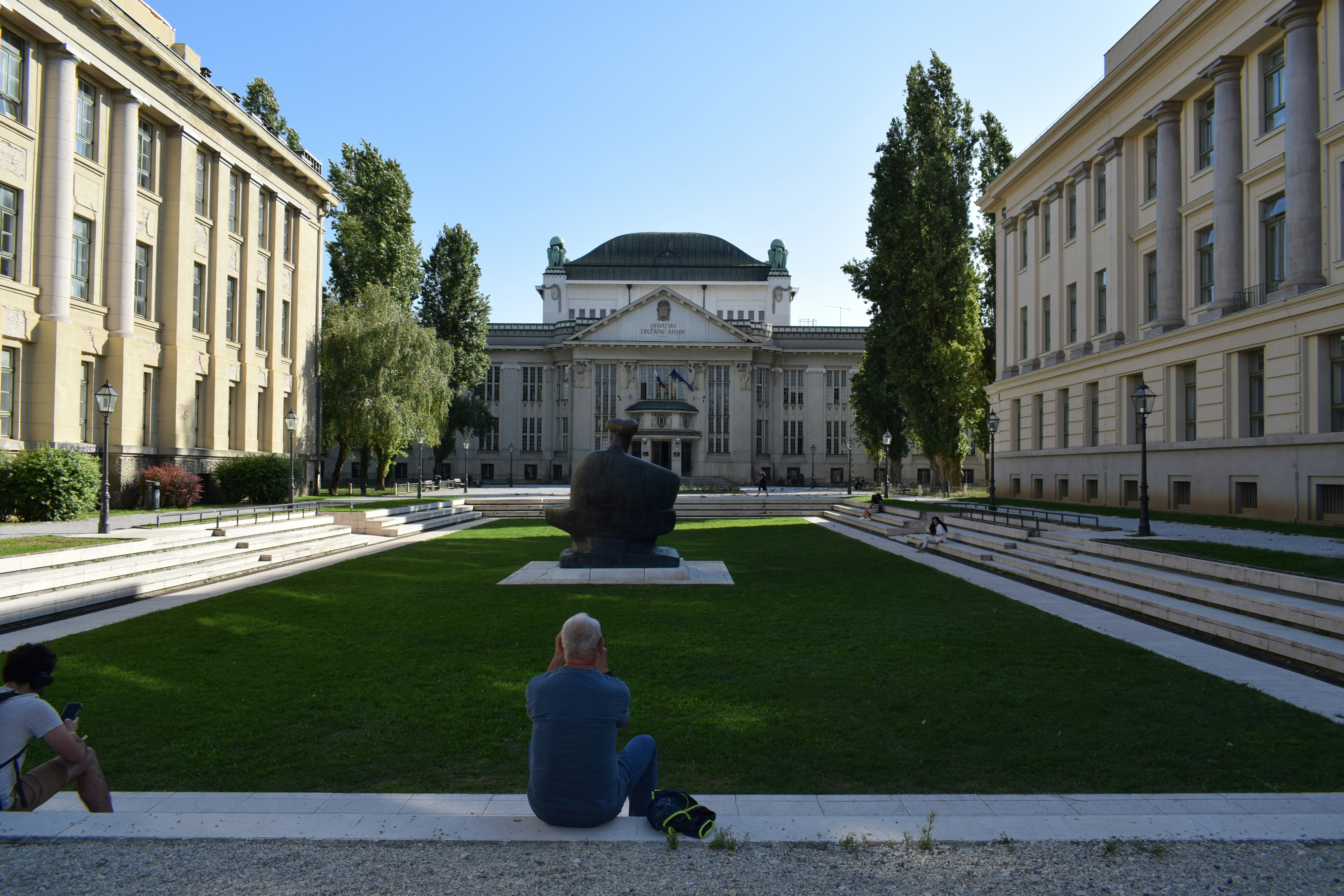 A group of people sitting on the ground in front of a building