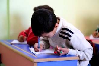 A young boy writing on a piece of paper