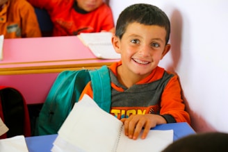 A young boy sitting at a table with a book in front of him