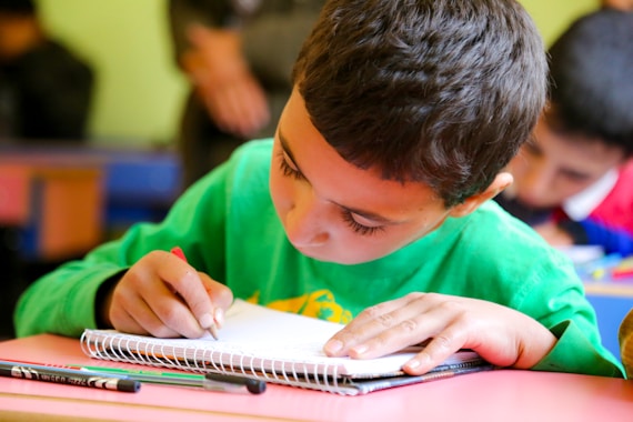A young boy sitting at a table with a book