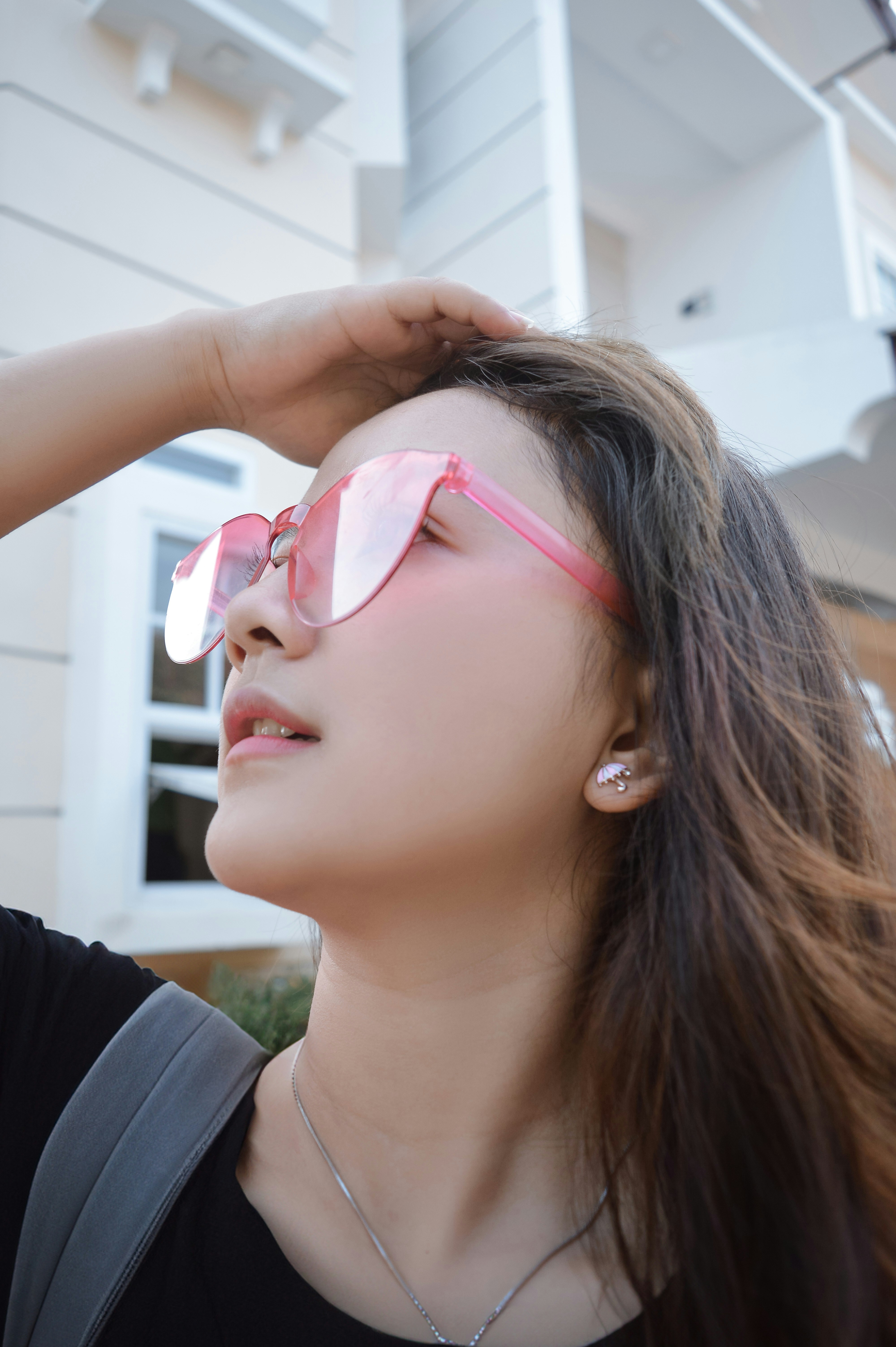 A woman wearing pink sunglasses standing in front of a house photo ...