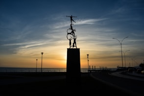 The sun is setting behind a statue of a man on a horse
