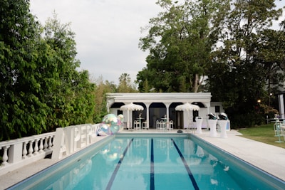A large swimming pool surrounded by lush green trees