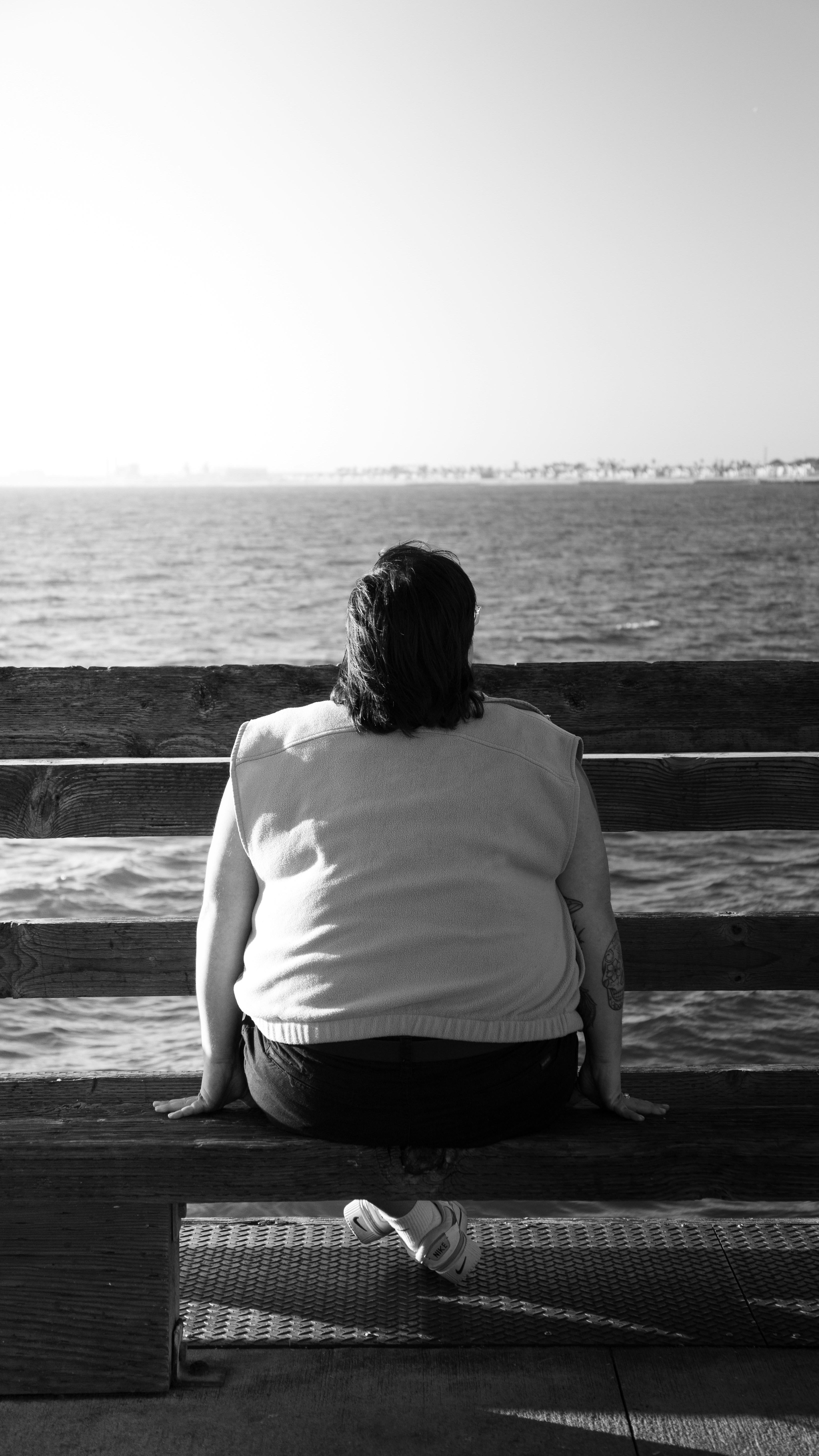 Eine Person, die auf einer Bank sitzt und auf das Wasser schaut