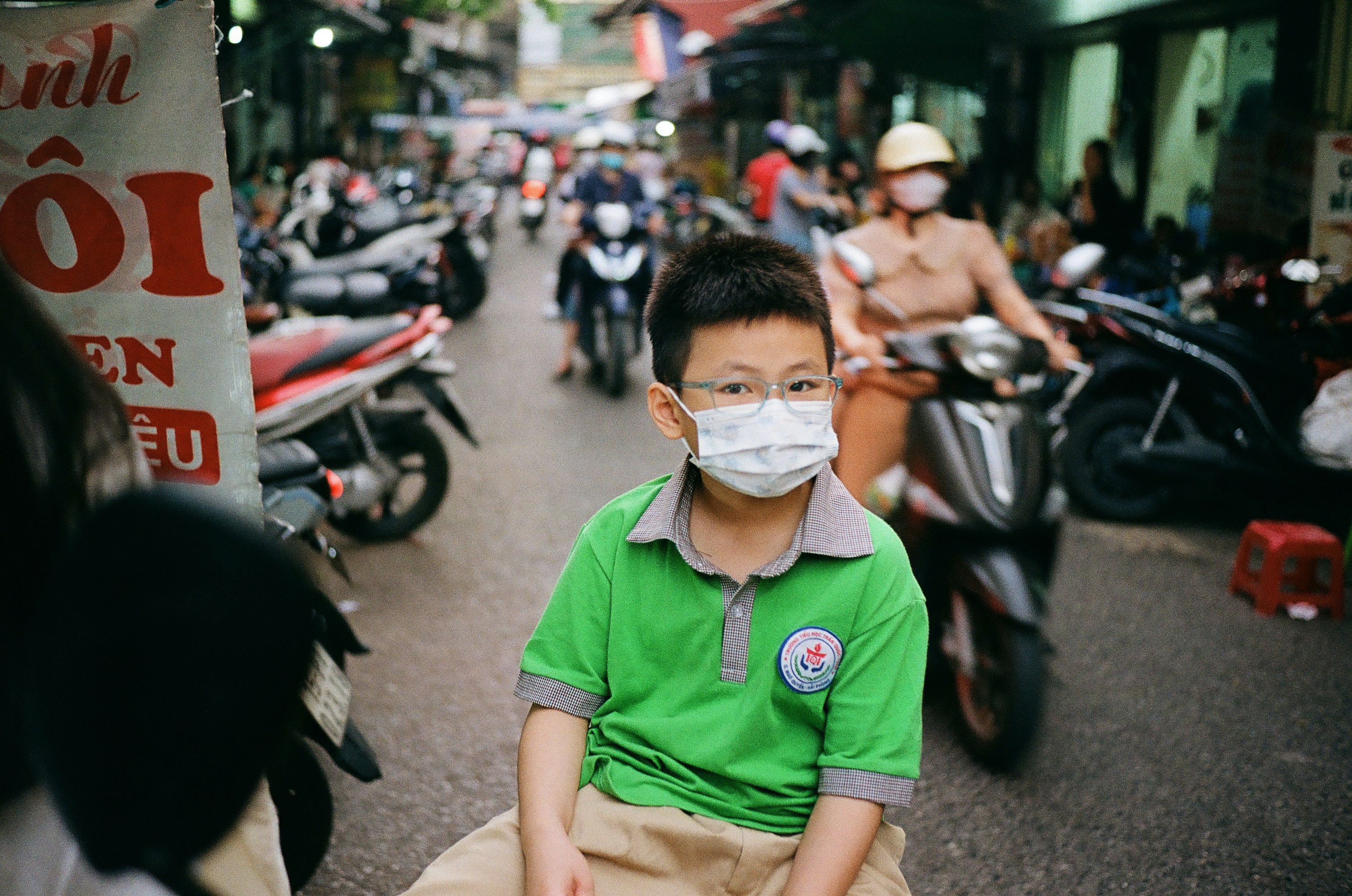 A young boy wearing a face mask on a busy street