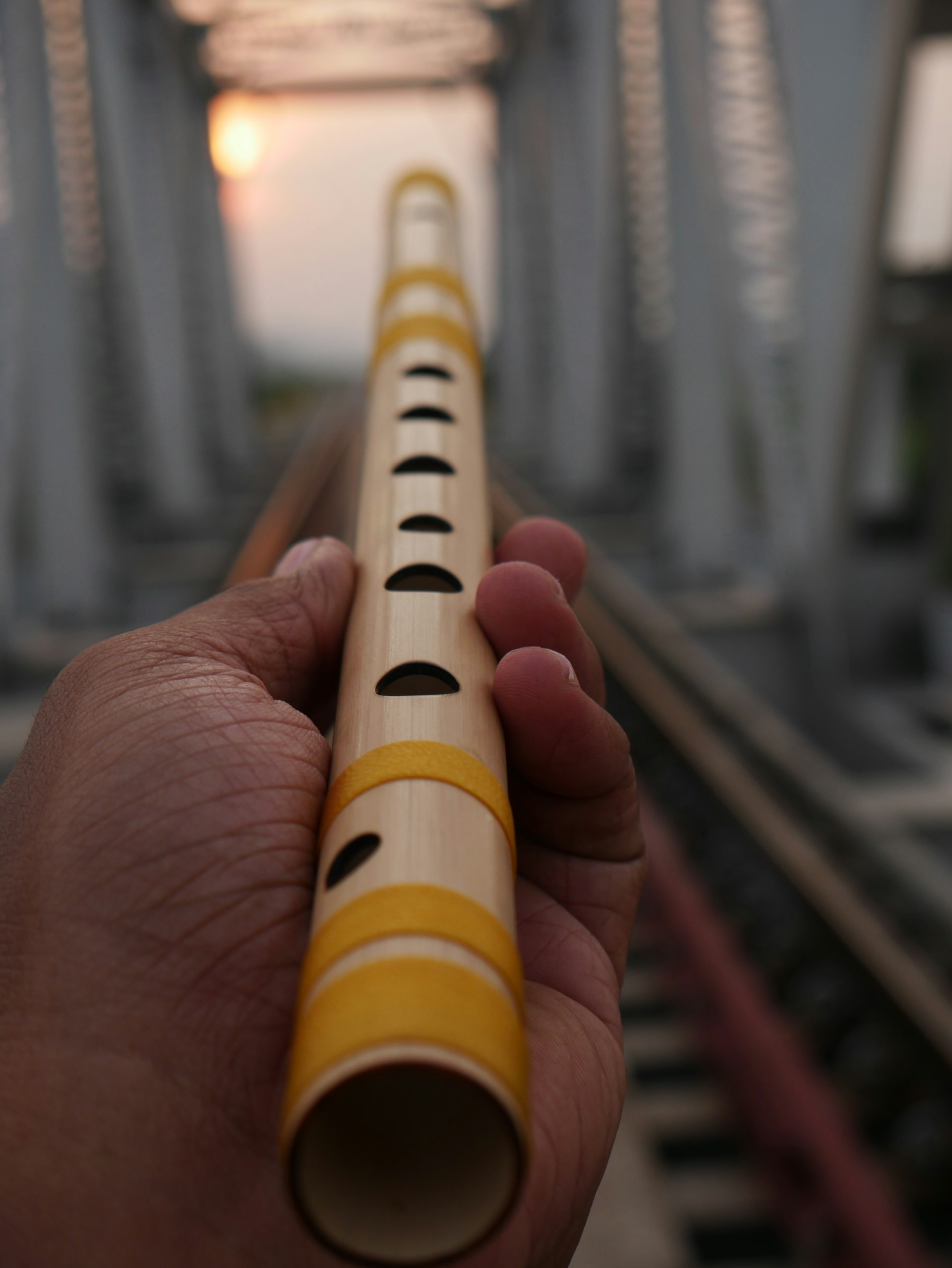 A hand holding a yellow and white tube on top of a train track
