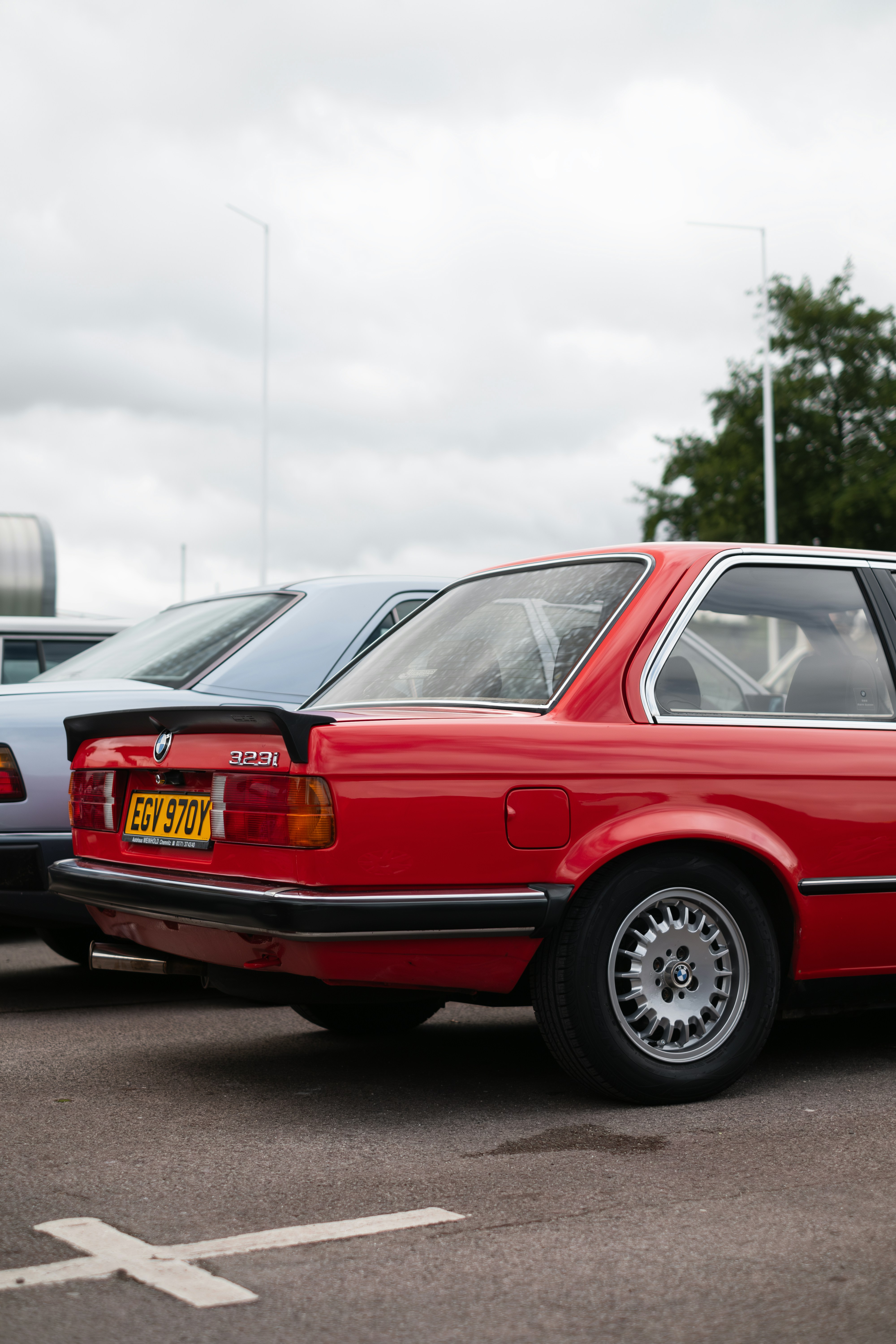 Un coche rojo aparcado en un aparcamiento junto a otros coches