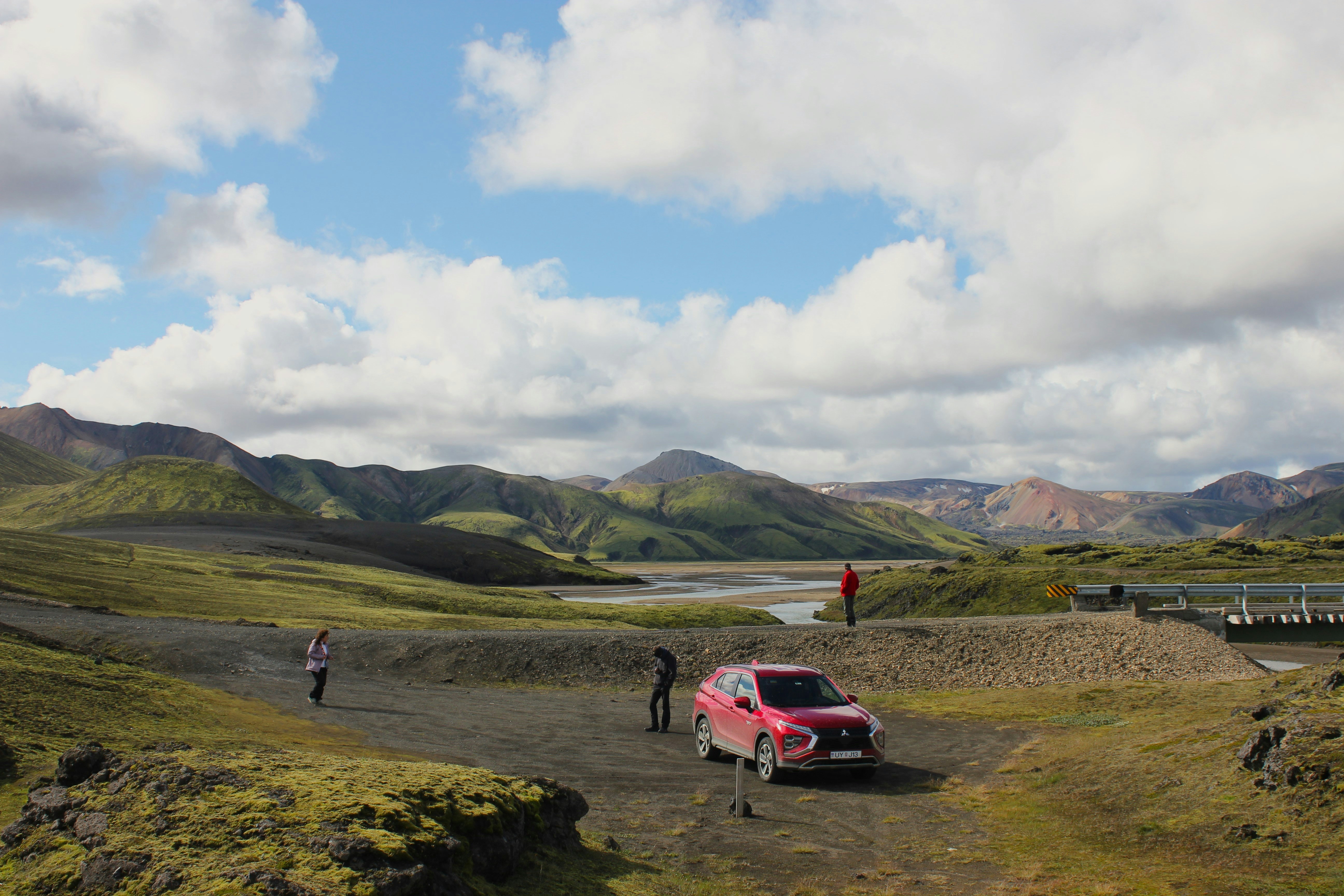A red car parked on top of a lush green hillside