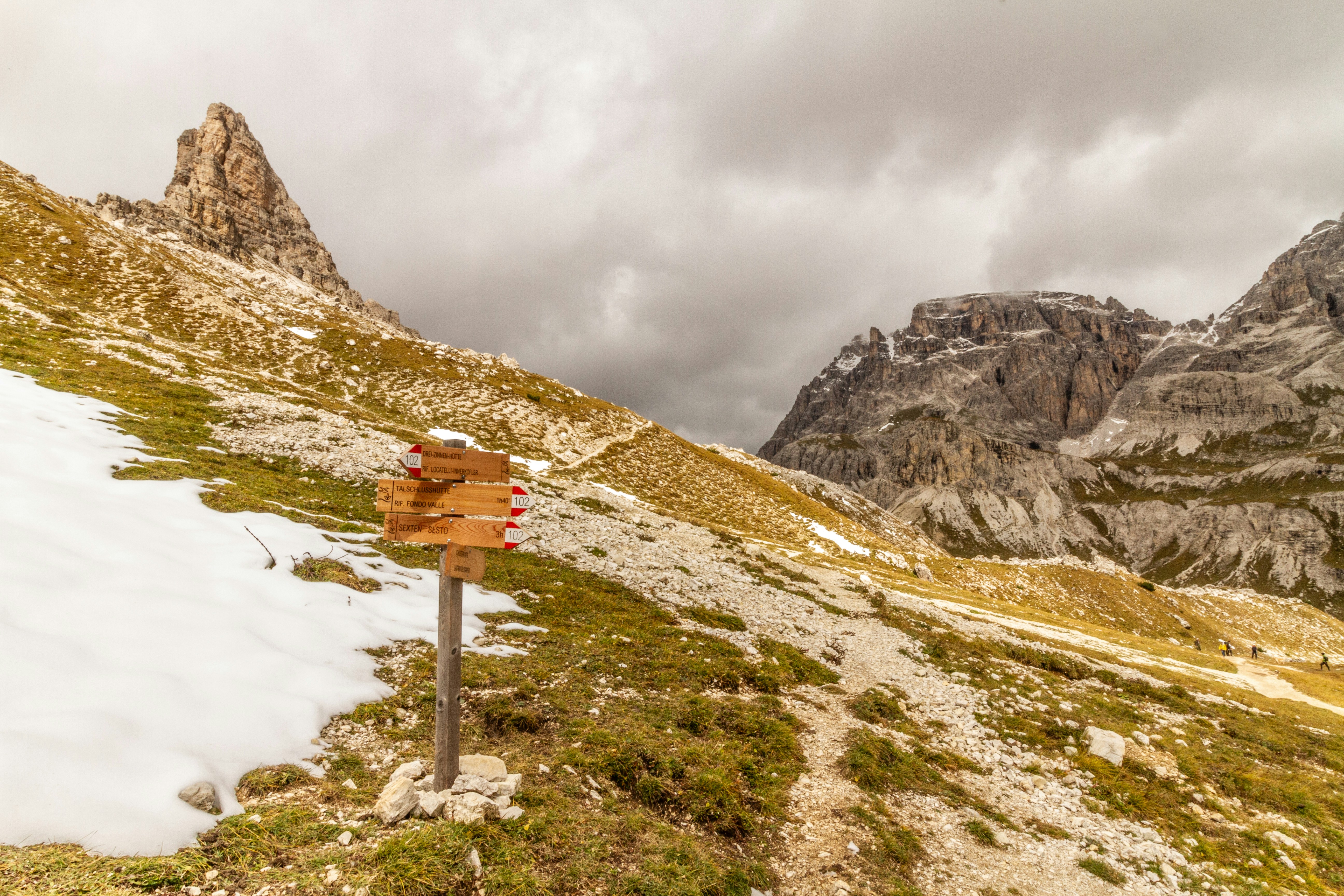 Wooden trail sign post stands in a vast mountain landscape.