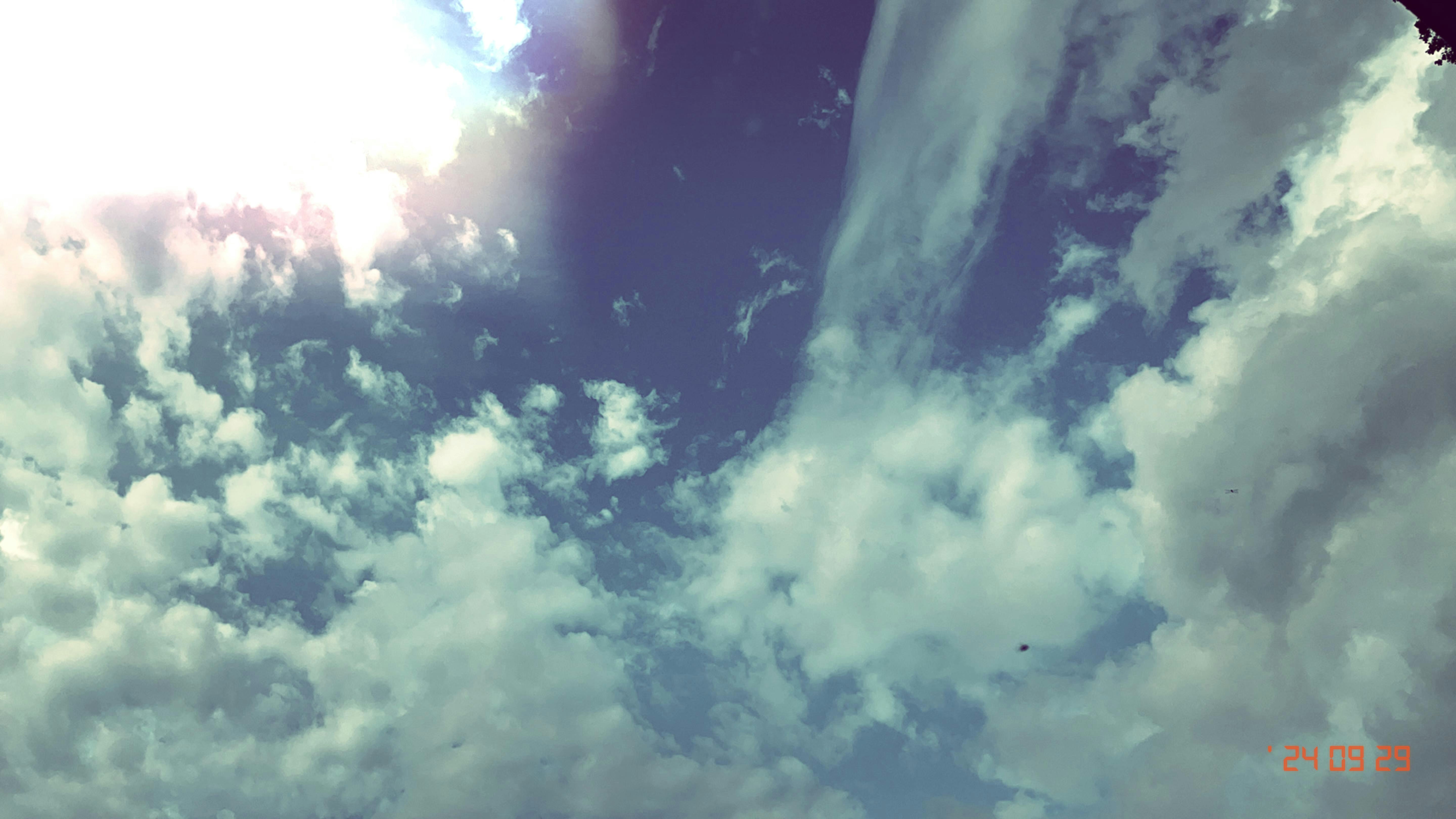 A plane flying through a cloudy blue sky