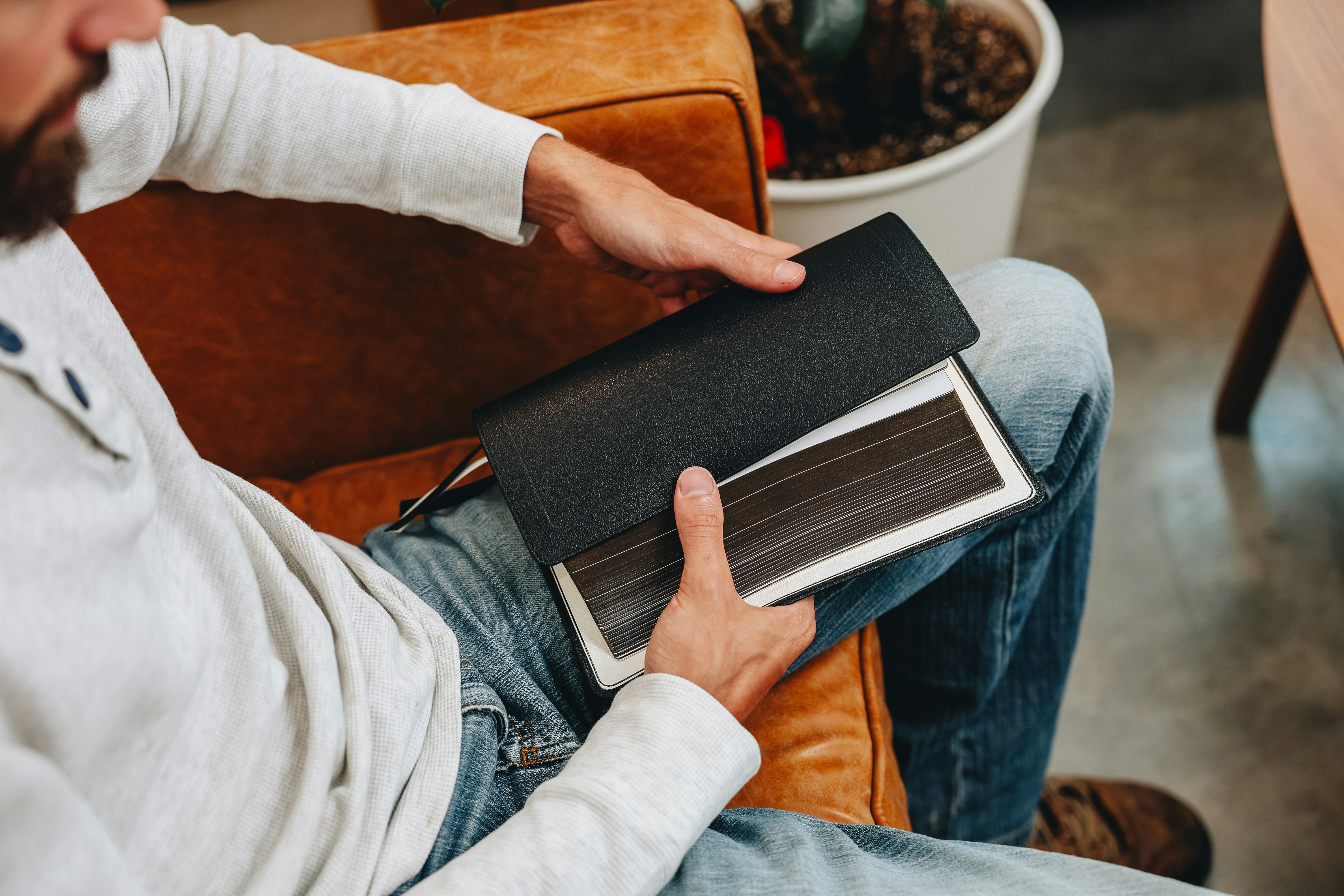 Ein Mann sitzt auf einem Stuhl und hält ein Buch in der Hand
