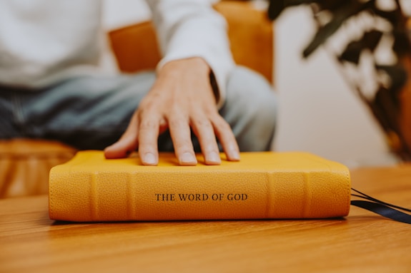 A person sitting on a chair with their hand on a book