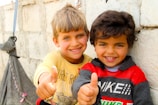 Two young boys giving the thumbs up sign