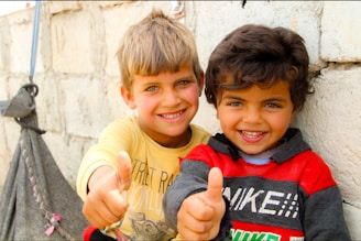 Two young boys giving the thumbs up sign