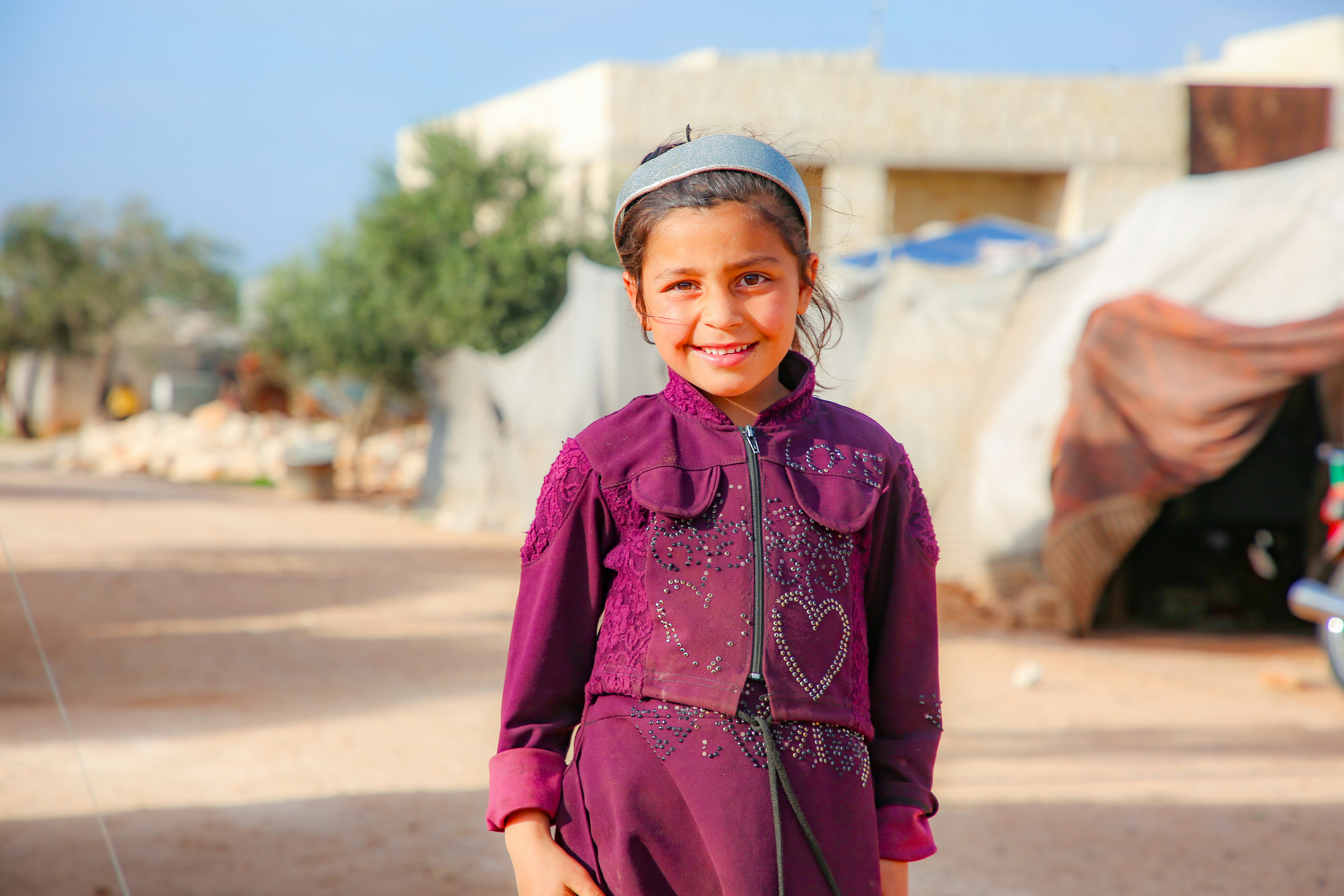 A young girl in a purple dress standing on a street