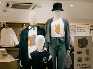Two mannequins wearing shirts and hats in a store