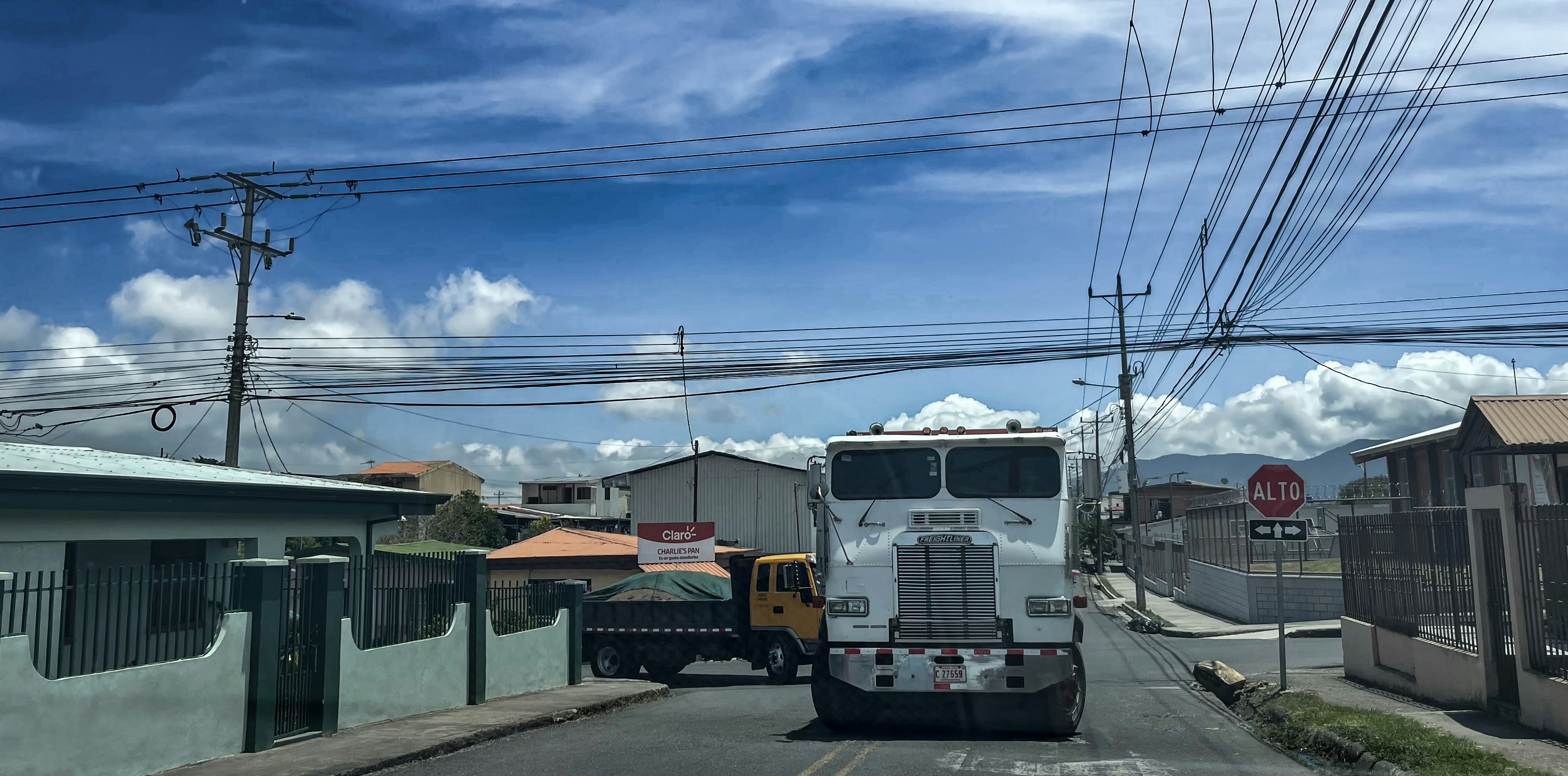 Commercial freight truck driving on open highway in bright daylight, blue sky, expansive road, clean surroundings