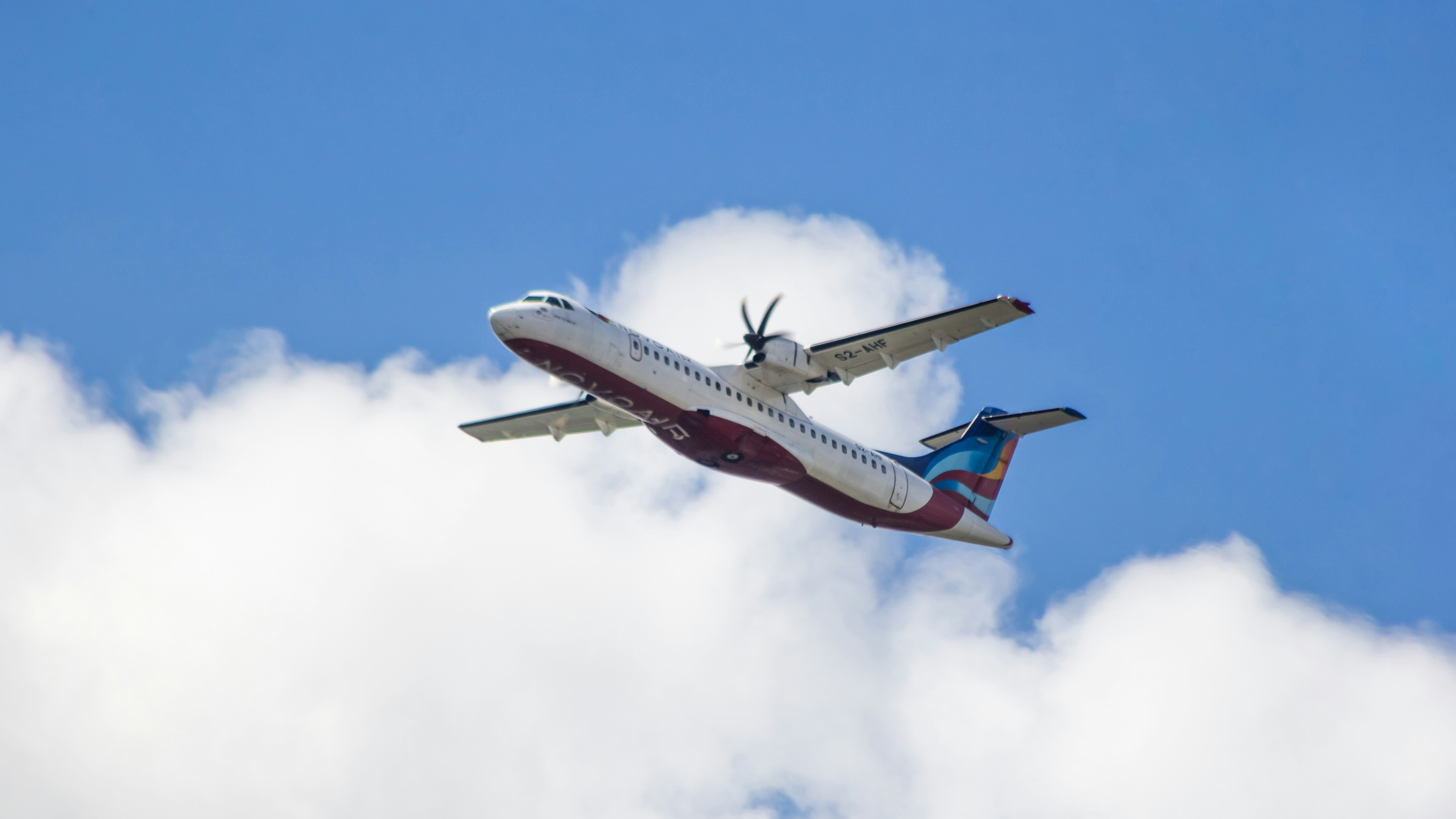 An airplane is flying in the sky with clouds, NovoAir ATR 72-500