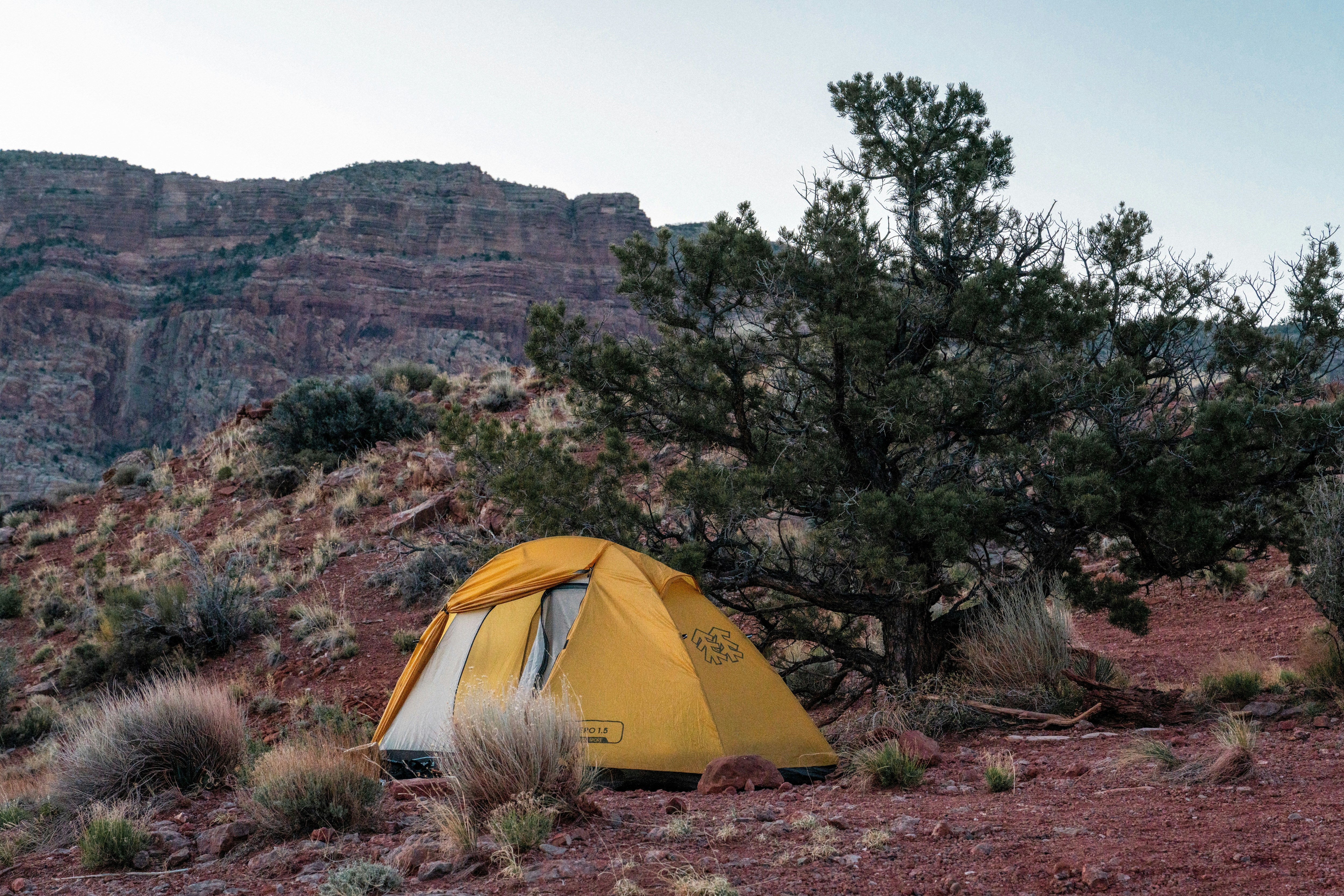A tent pitched up in the desert with mountains in the background