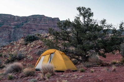 A tent pitched up in the desert with mountains in the background